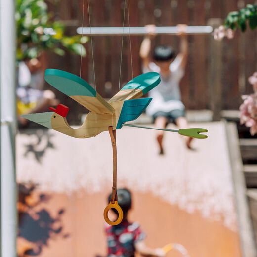 Bird pinewood mobile toy in natural and pastel tones by Eguchi hung outdoor